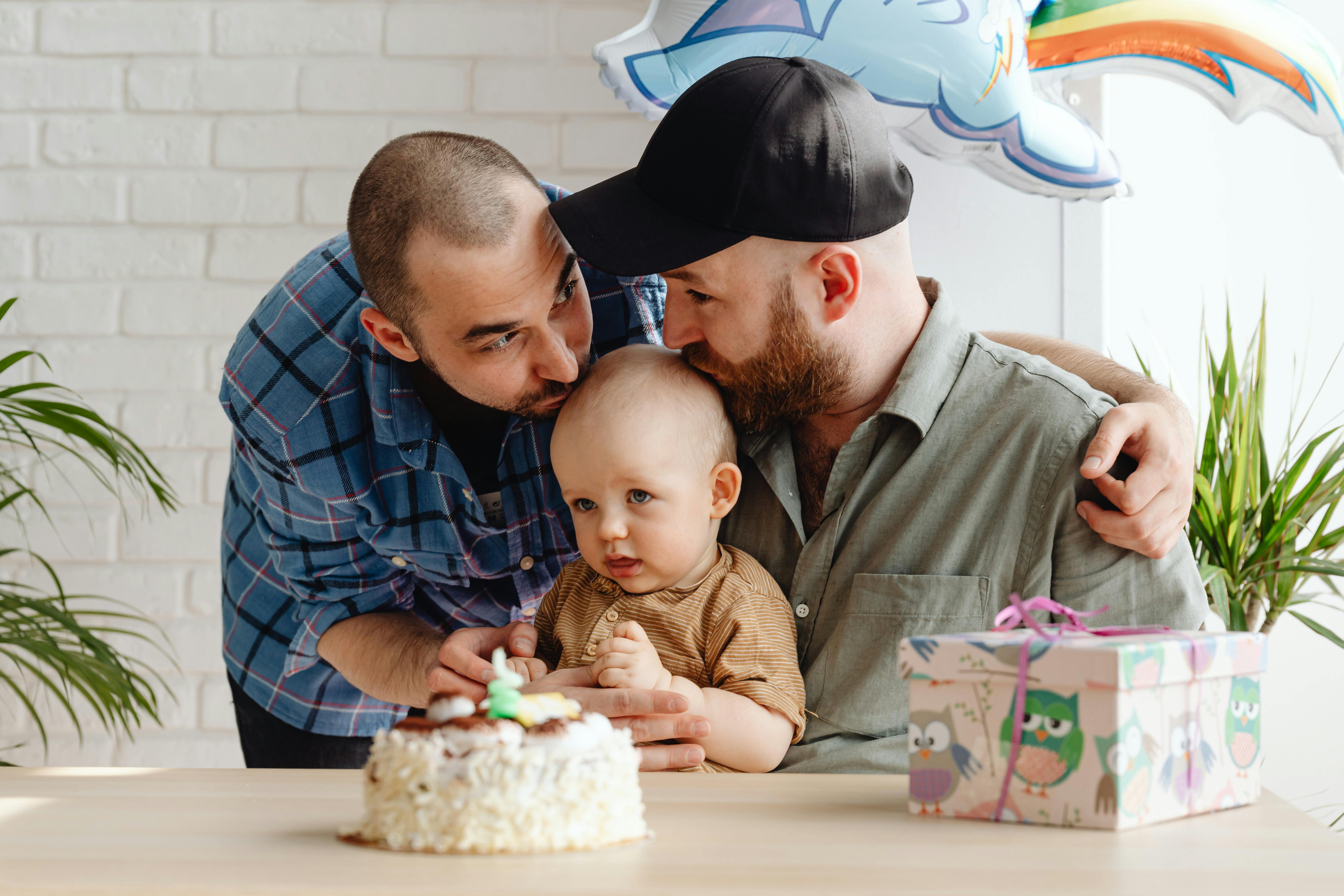 a same sex couple kissing their baby together