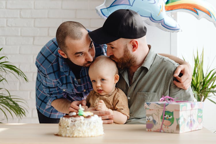 A Same Sex Couple Kissing Their Baby Together