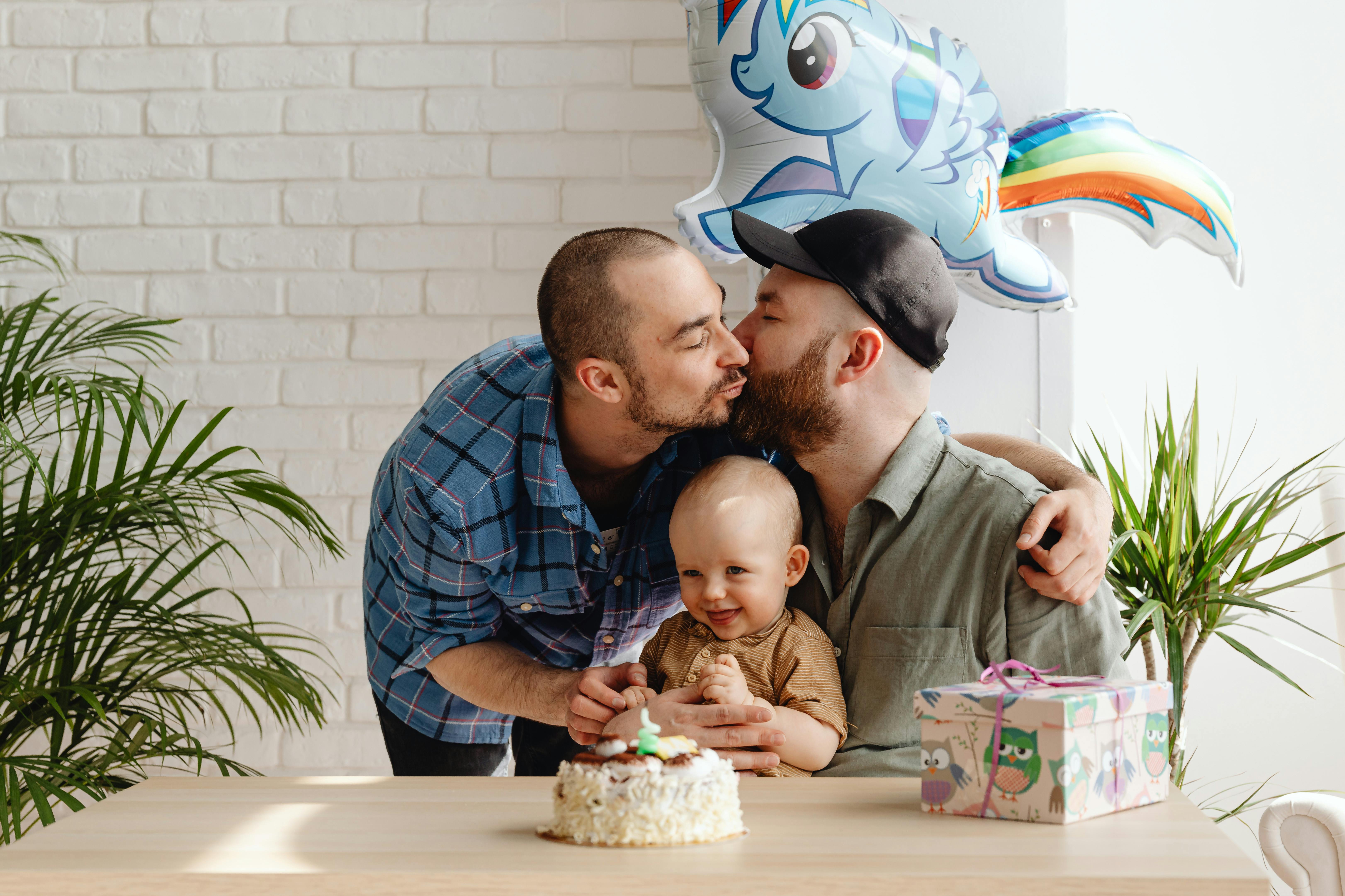 smiling baby in the arms of his father kissing his partner