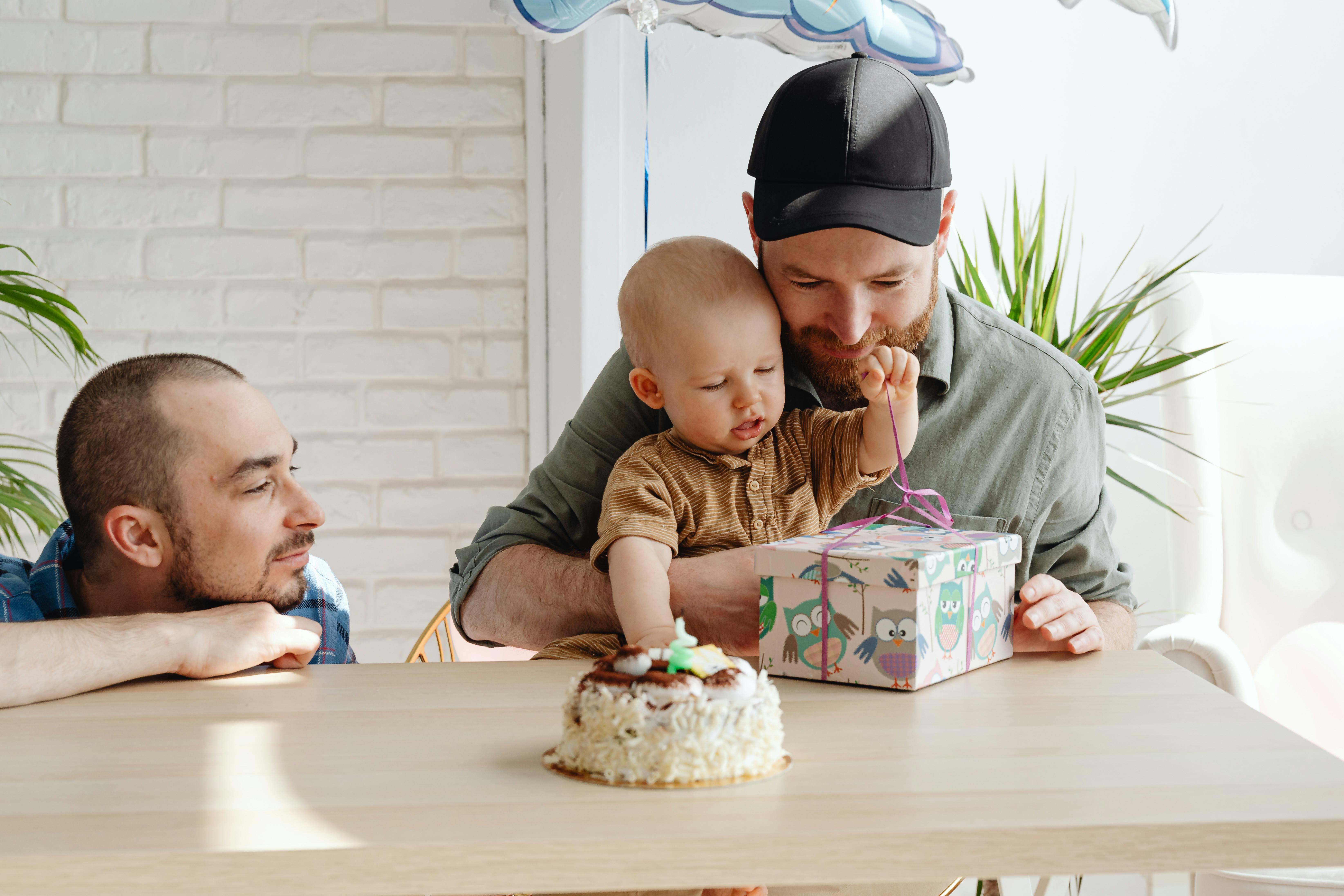 a man holding his son while unwrapping the gift on the table