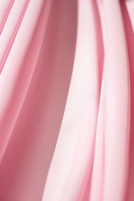 Soft pink textile with delicate wavy patterns creates a smooth and minimalistic backdrop.