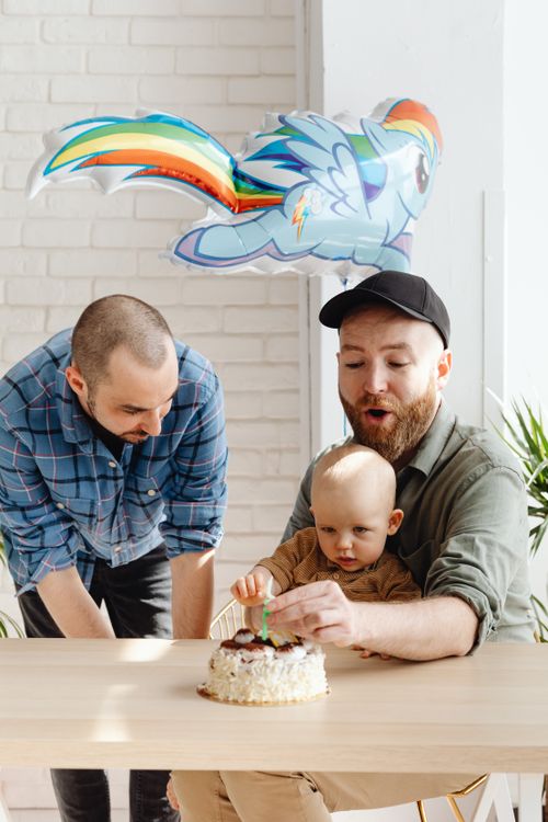Free A joyful indoor celebration of a baby's birthday with parents, cake, and a fun balloon. Stock Photo