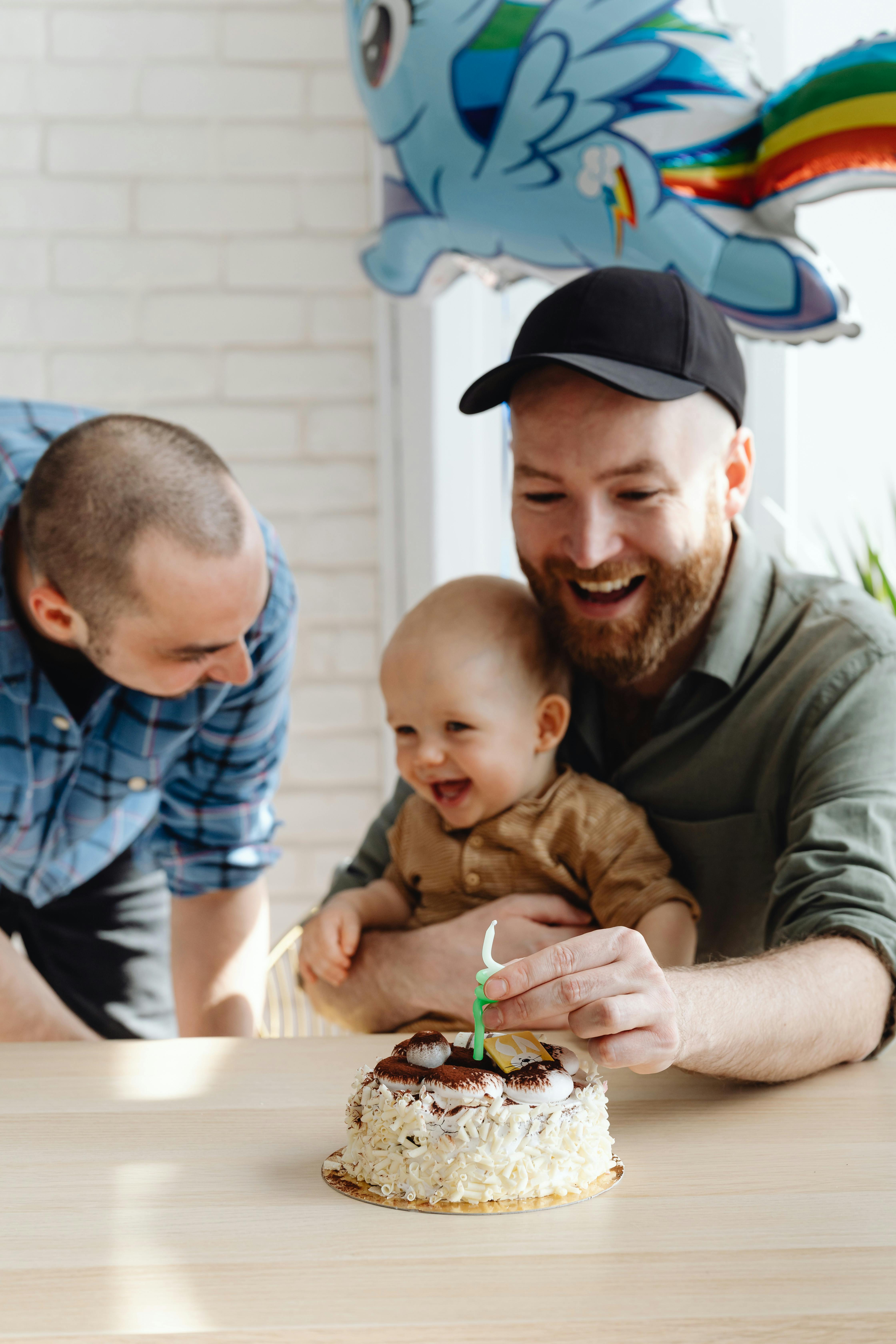 man in black cap holding a baby smiling