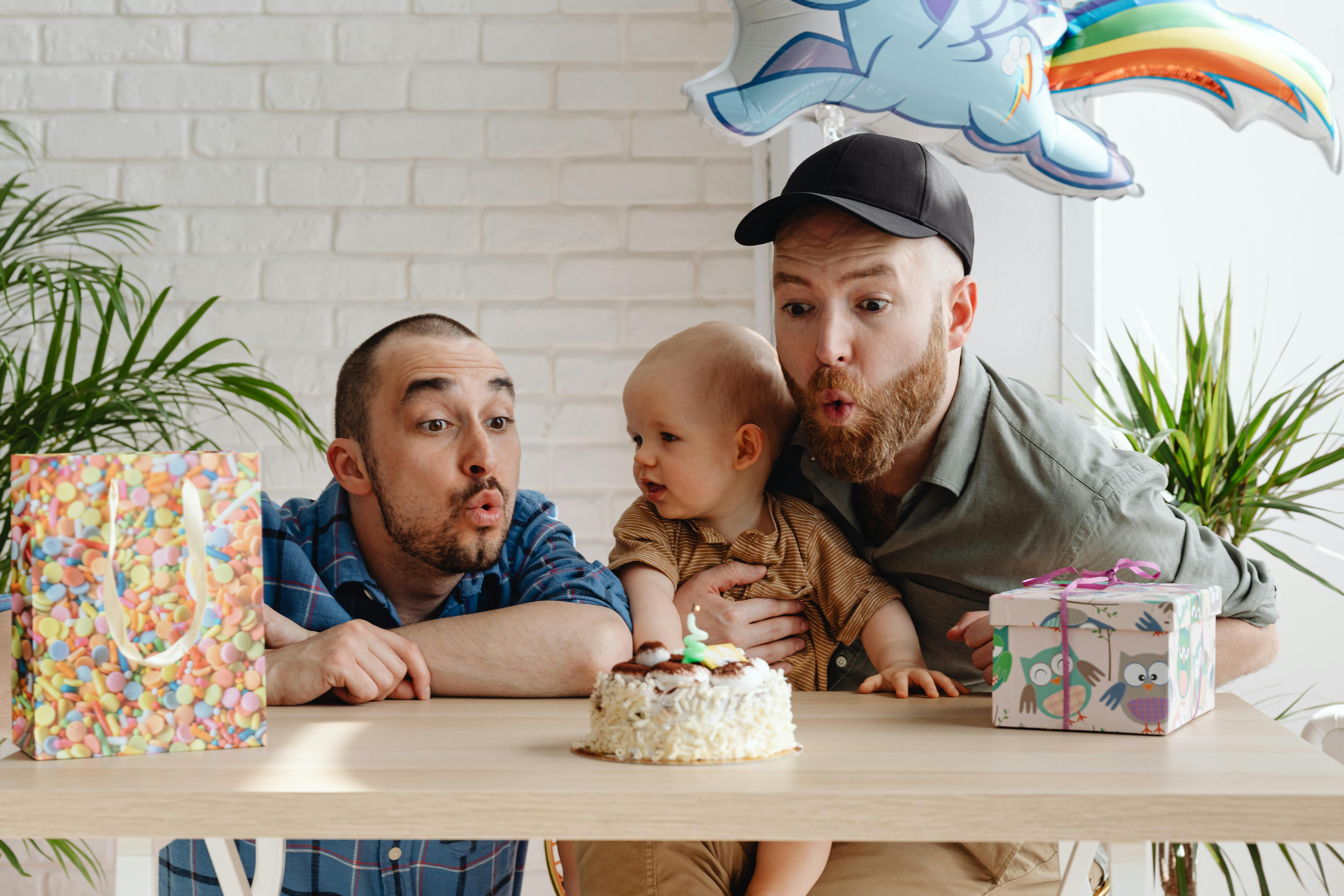 two men blowing a birthday cake