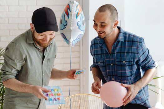 Two friends enjoy a cheerful birthday celebration indoors with balloons and laughter.