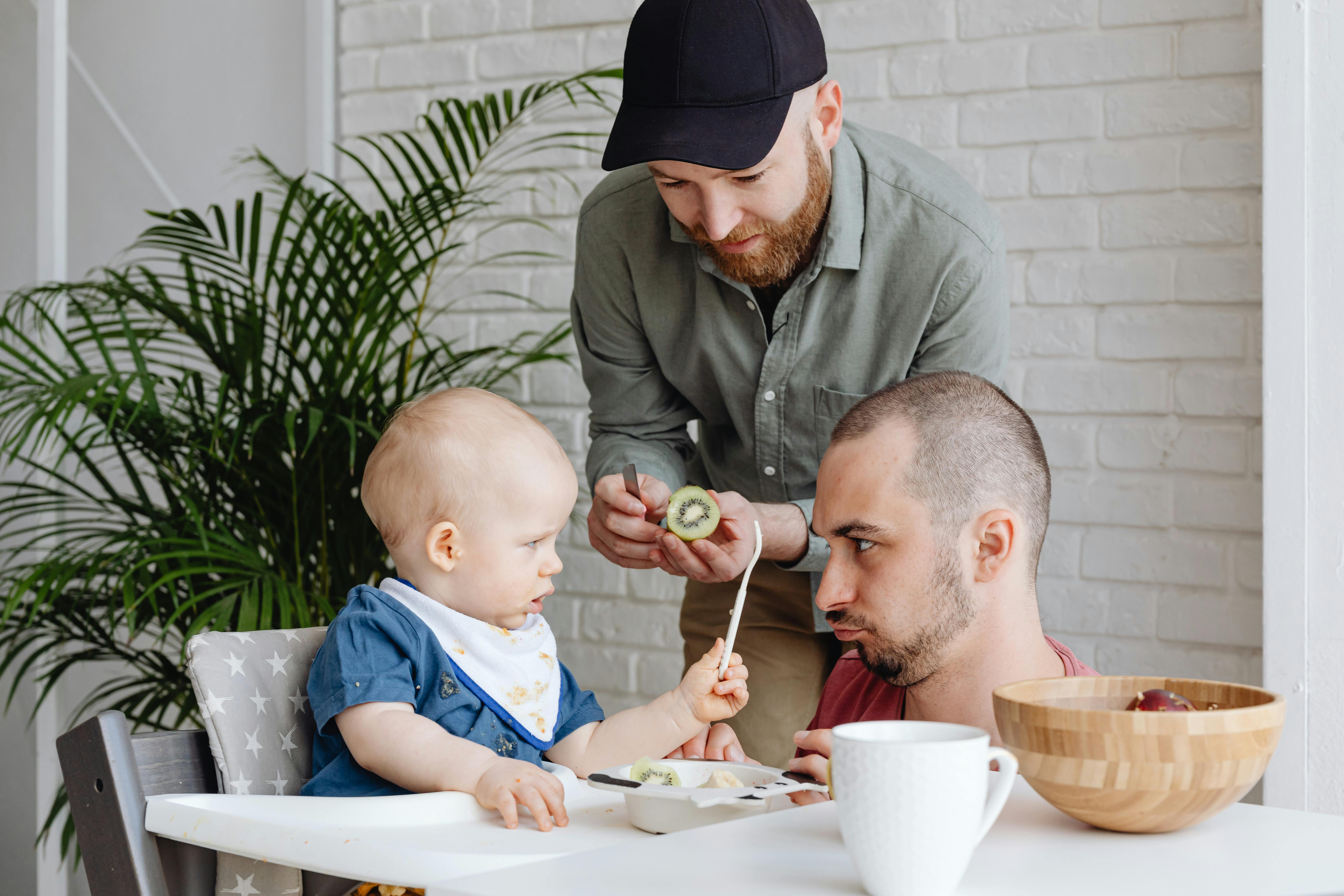 two men feeding a baby boy