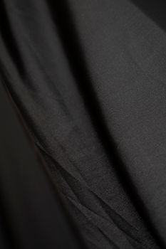 Detailed close-up view of black satin fabric showcasing its soft and textured surface.