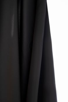 A minimalist still life of black drapes against a contrasting white backdrop.