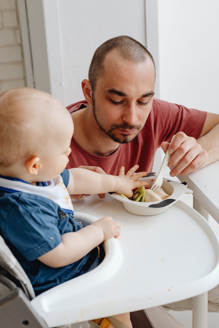 A Man Feeding A Boy 