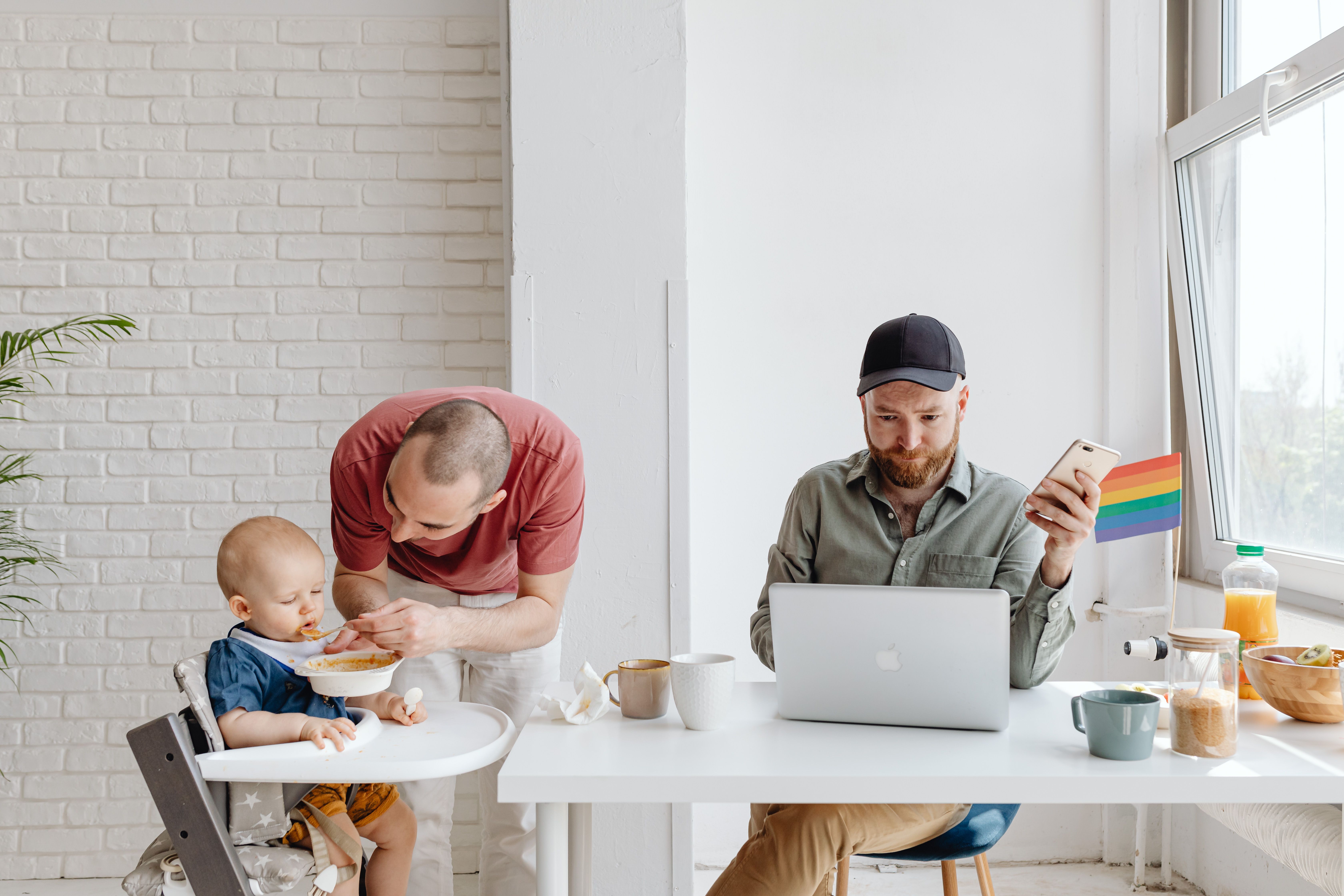 A gay couple managing family breakfast with a baby, featuring modern parenting dynamics.
