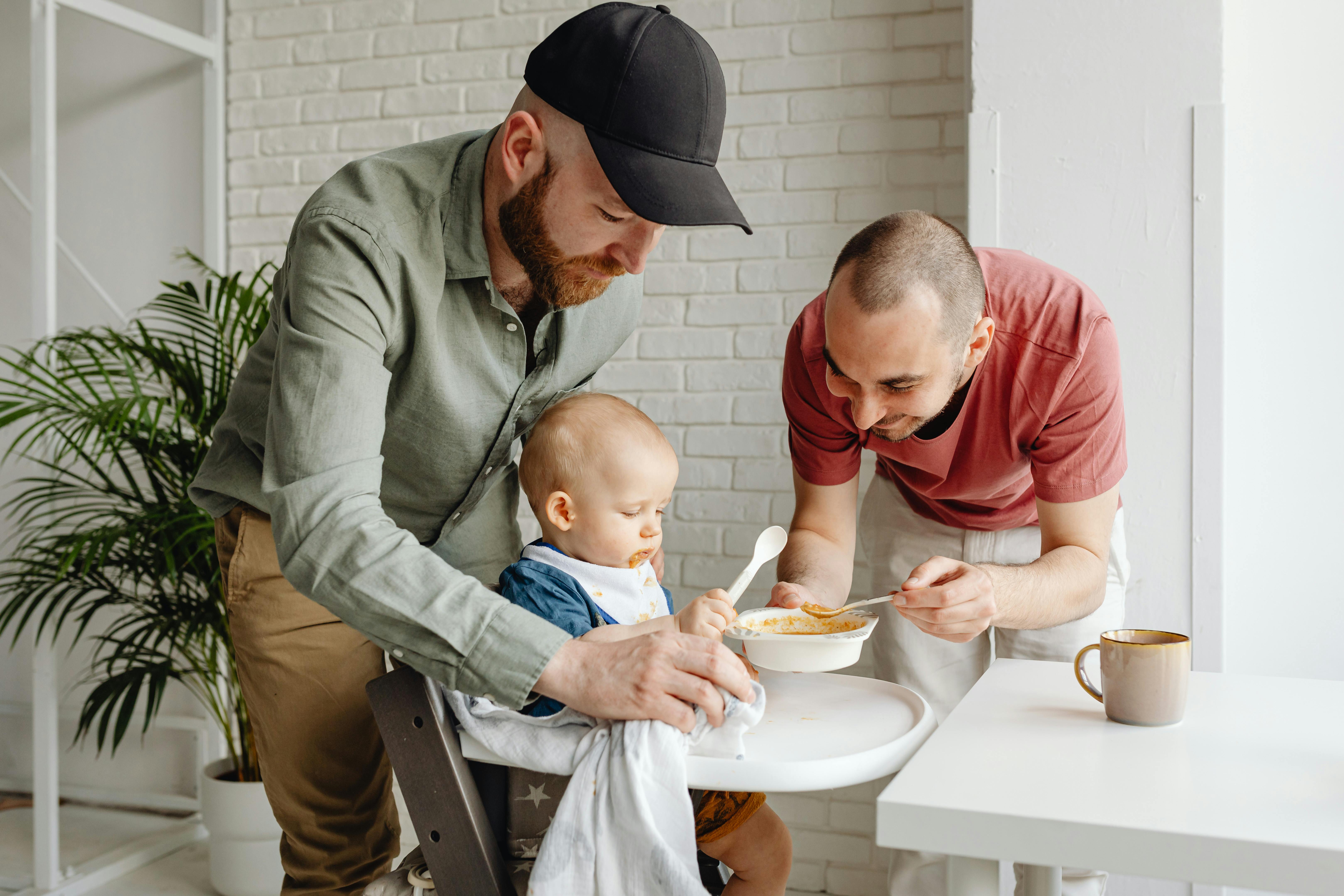 a same sex couple feeding their baby