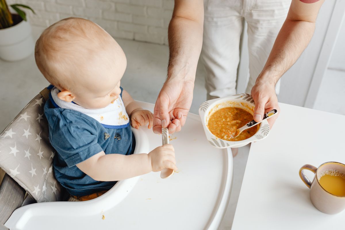 Parent feeding a baby in a high chair
