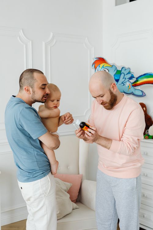 Free A gay couple engaging with their baby in a brightly decorated room. Stock Photo