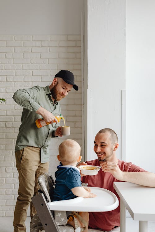 Parents Spoon Feeding a Baby and Pouring Juice