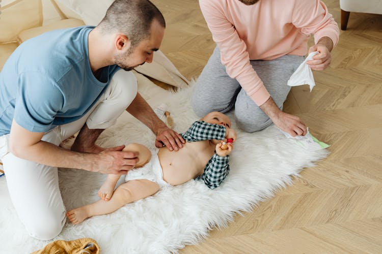 A Man Holding A Baby Lying On A White Furry Rug