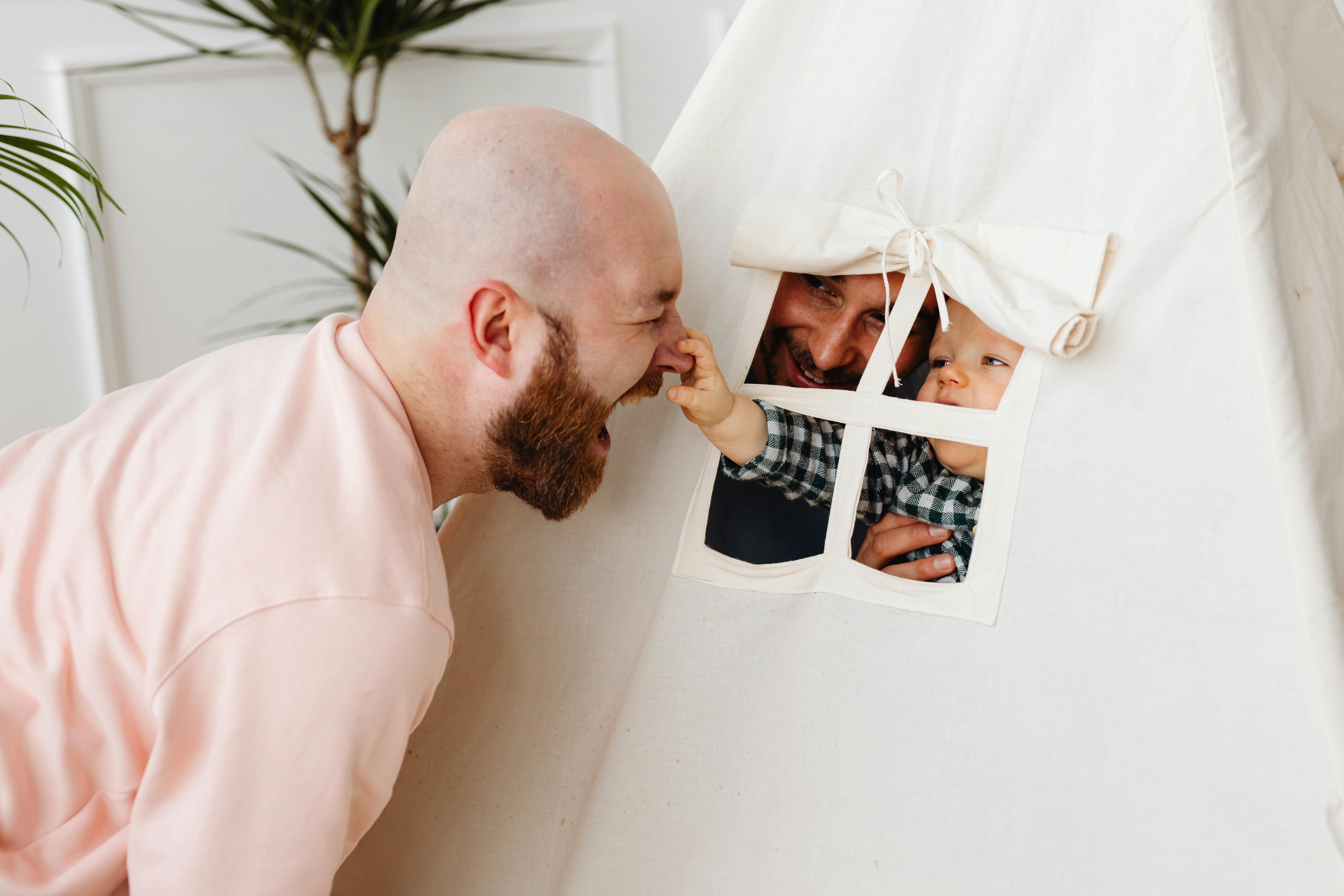 baby grabbing his father nose through the tent window