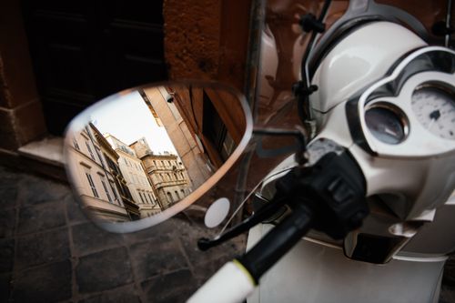 Free Reflection of classic European buildings in a scooter's side mirror on a cobblestone street. Stock Photo