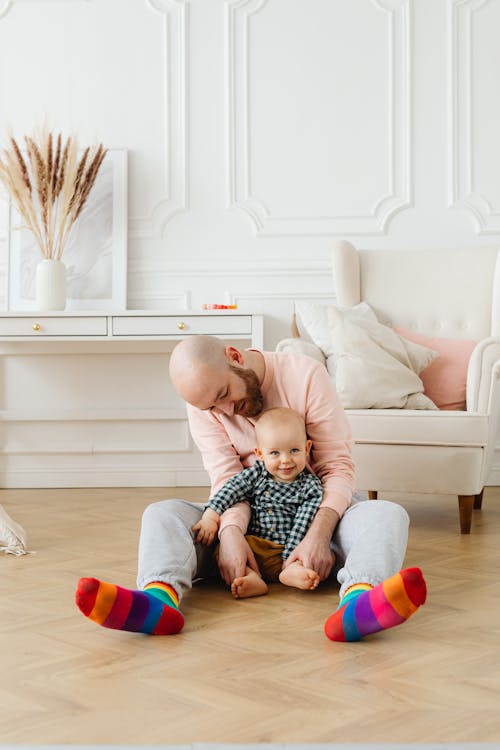 Free Man Sitting and Cuddling A Baby Stock Photo