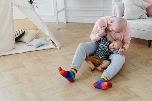 Free A Man Holding Hands of His Son while Sitting on the Floor Stock Photo