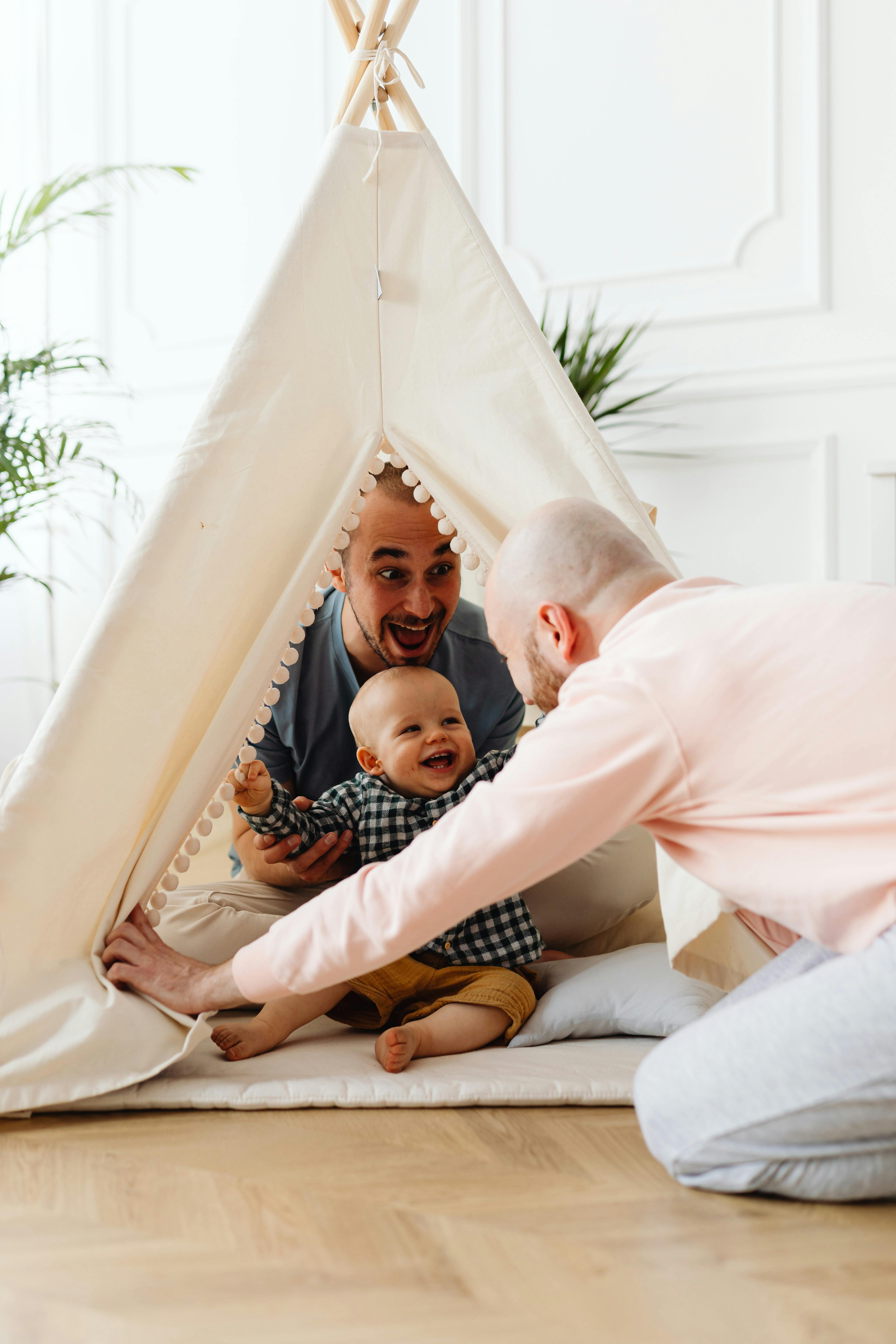 a couple playing with their baby in a teepee indoors