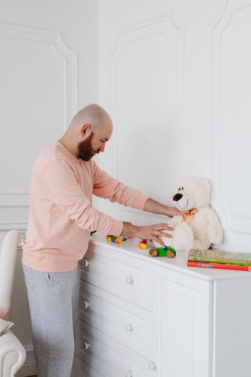 Free A Bearded Man Fixing Toys on Top of a White Drawer Stock Photo