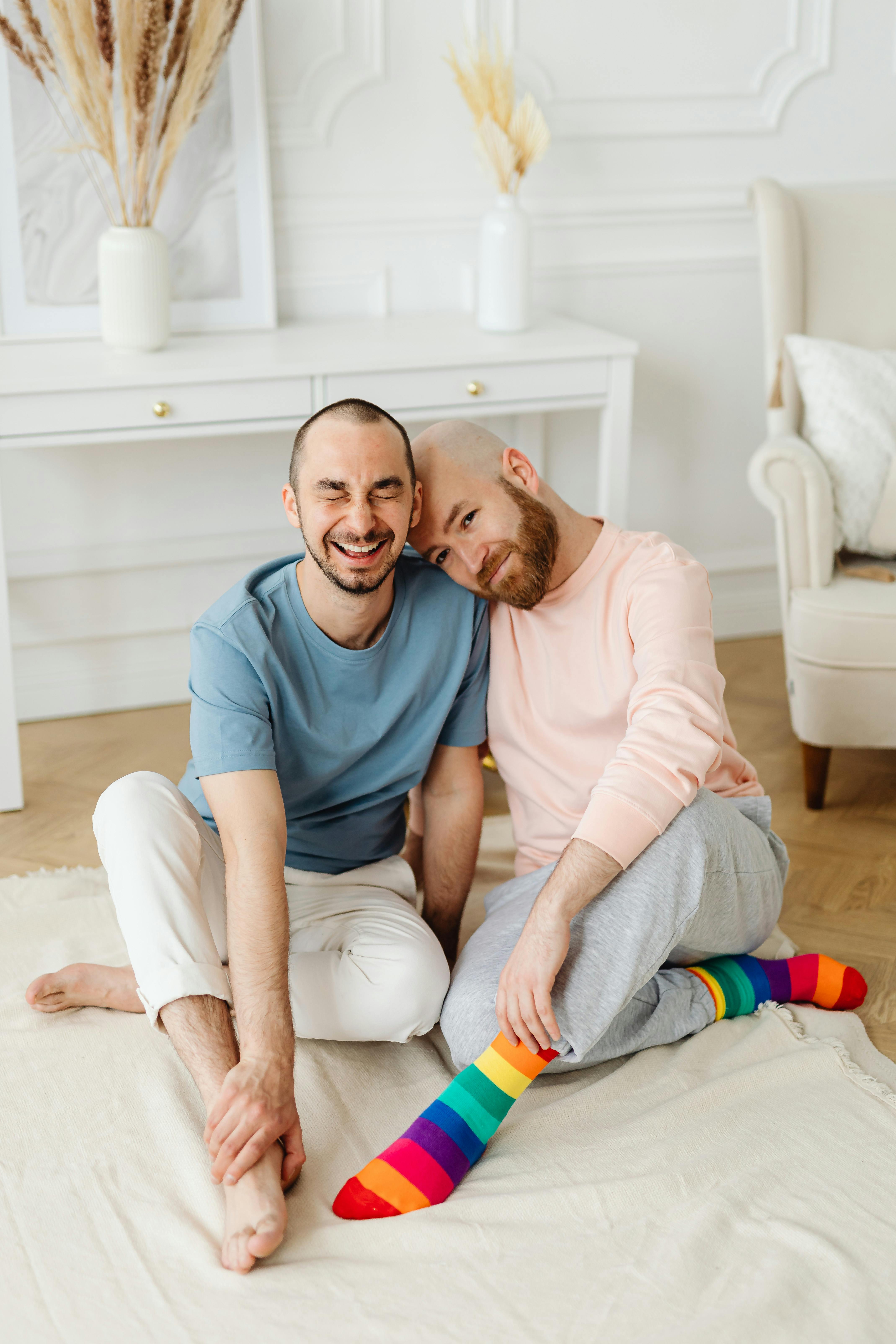 a man in pink sweater leaning on his partner s shoulder while sitting on the floor