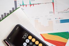 Top view of financial reports with a calculator app open on a smartphone.