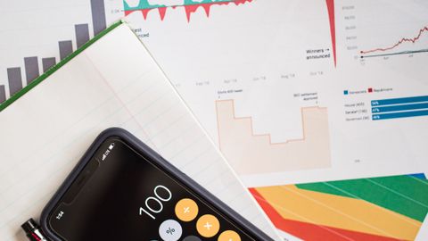 Top view of financial reports with a calculator app open on a smartphone.