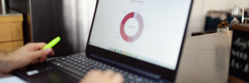 Person analyzing business data on a laptop in a modern indoor setting.