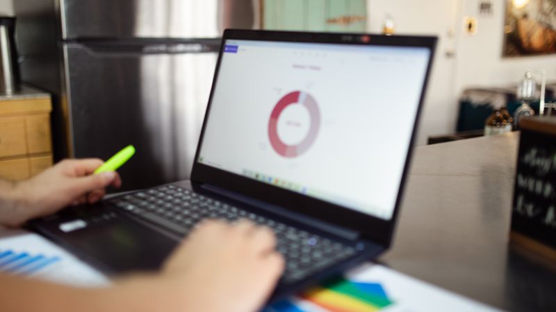 Person analyzing business data on a laptop in a modern indoor setting.