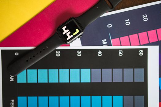 A smart watch resting on vibrant charts showing data visualization on a table.