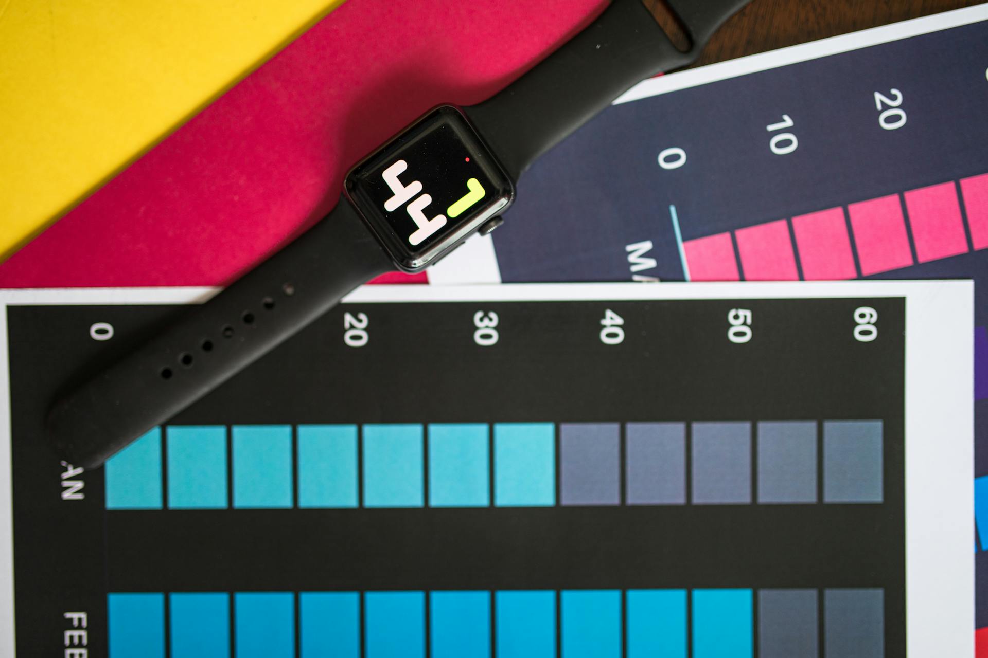 A smart watch resting on vibrant charts showing data visualization on a table.