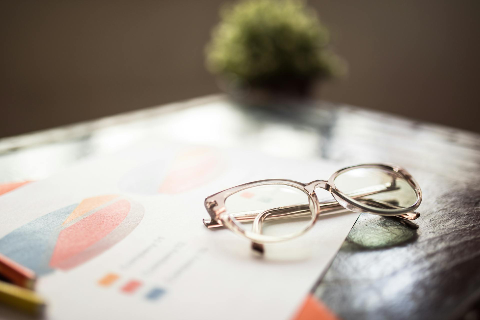 Eyeglasses placed on a business document with financial graphs and charts.