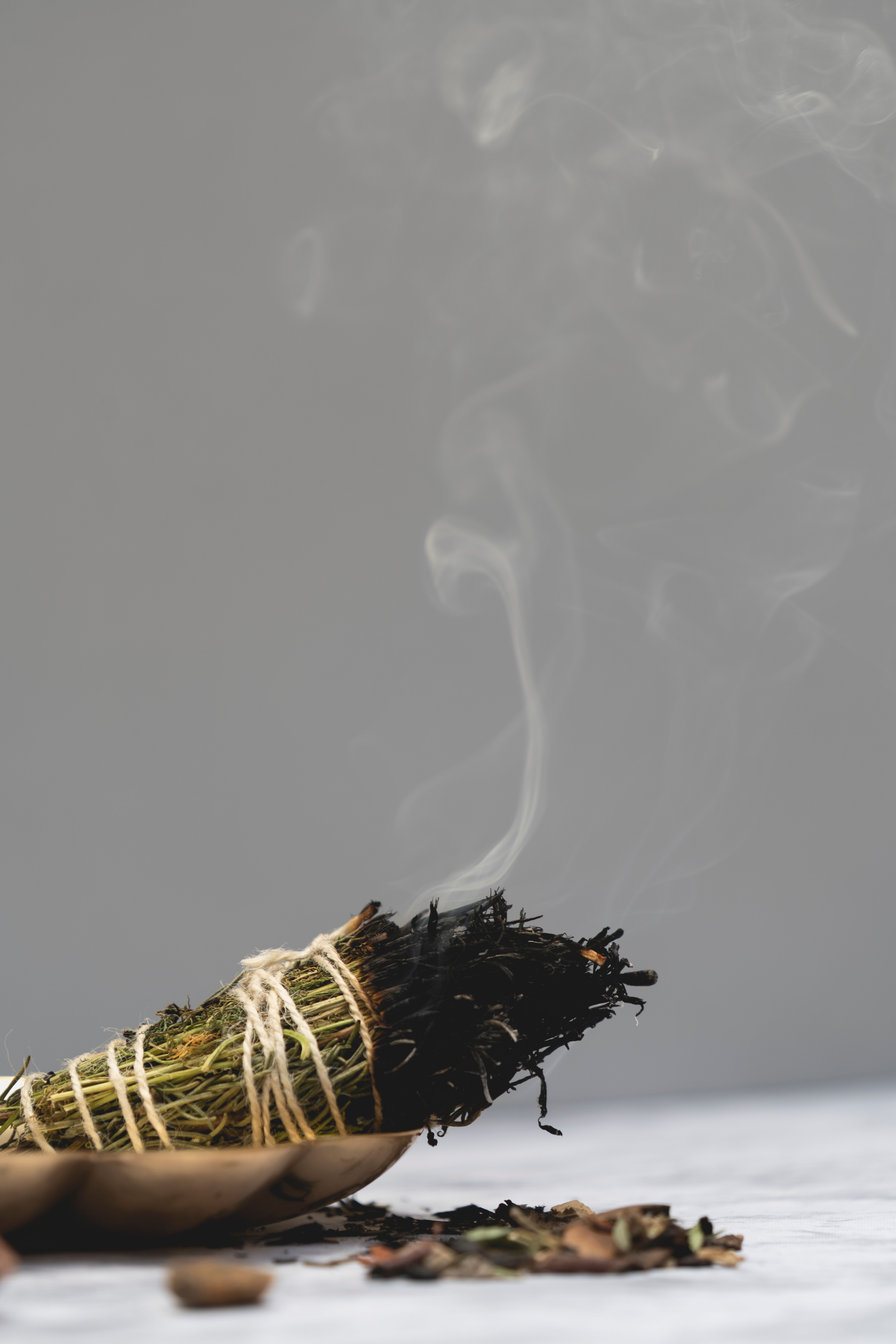 Close-up of aromatic incense stick burning, releasing a gentle smoke trail against a neutral background.