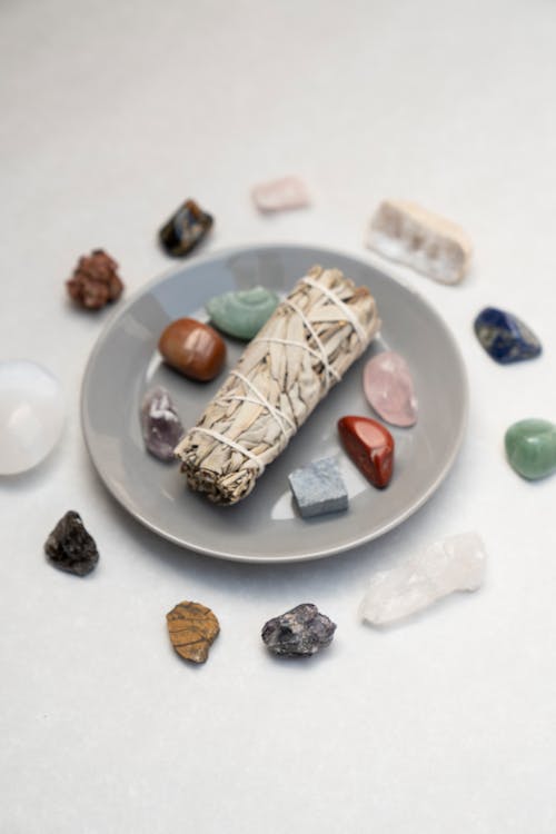 Small Bundle of Dried Herbs Amidst Polished Pebbles and Minerals