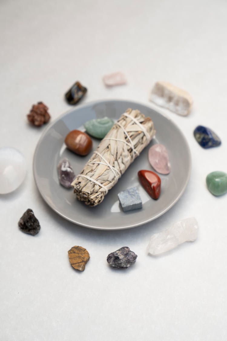 Small Bundle Of Dried Herbs Amidst Polished Pebbles And Minerals