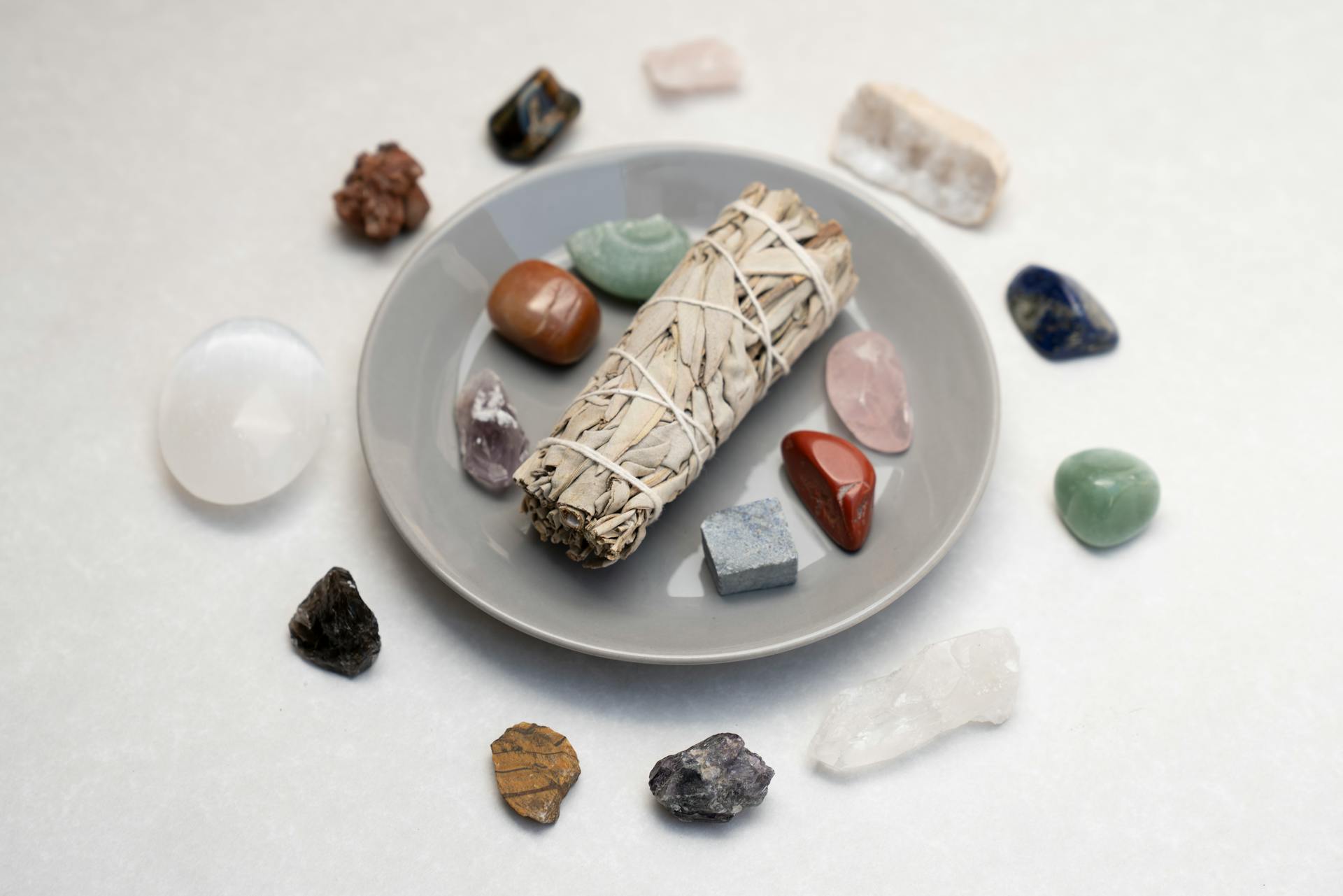 Ceramic plate with sage smudge stick and healing crystals for spiritual rituals.