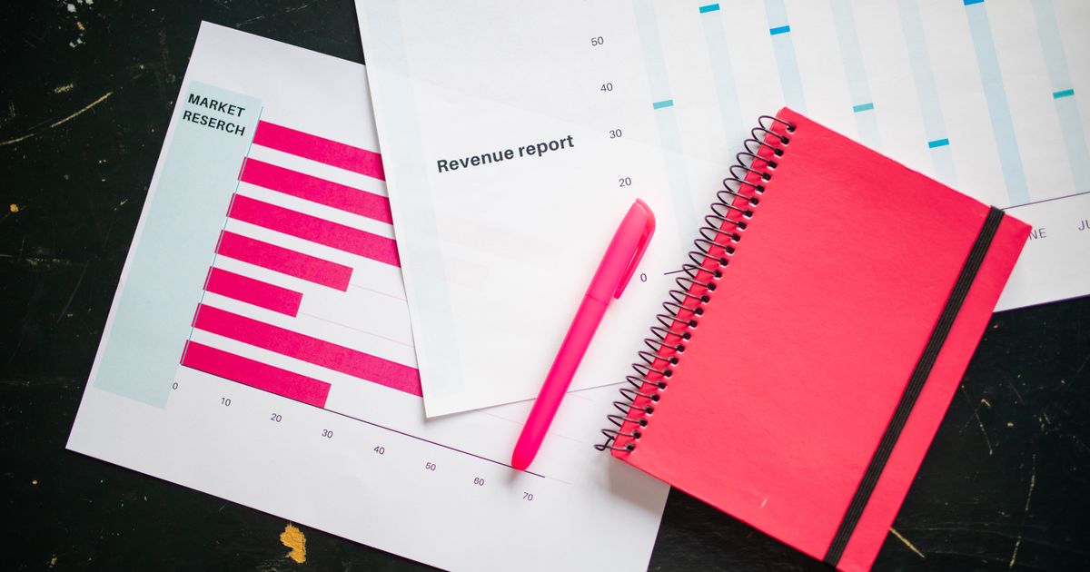 Overhead shot of a desk with charts, a red notebook, and a pen for business analysis.