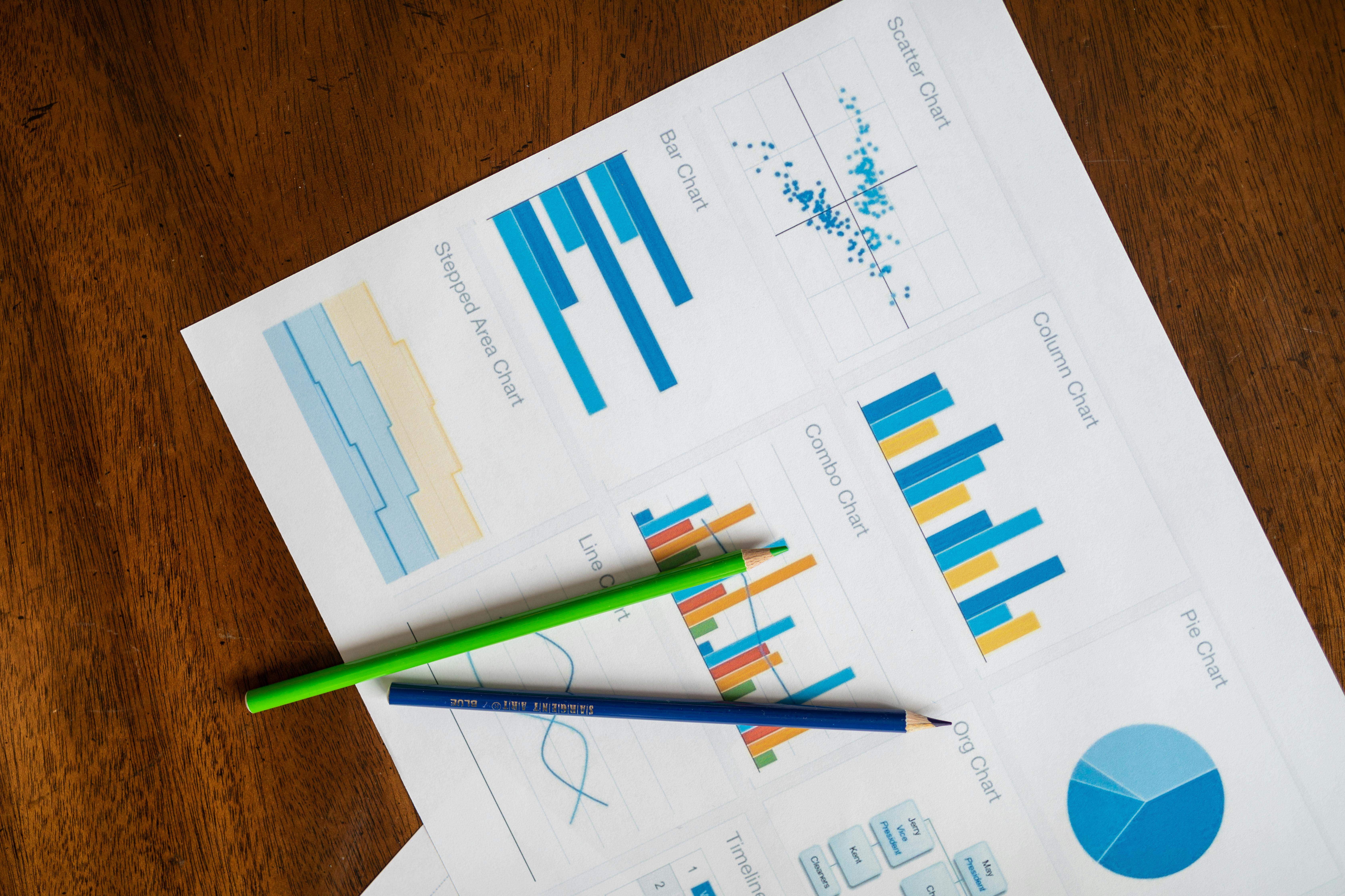 Top view of vibrant charts and colored pencils on wooden surface.
