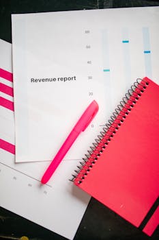 Revenue report with a pink notebook and pen on a bright flatlay, perfect for business presentations.