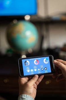 Close-up of hands holding a smartphone displaying a business chart indoors.