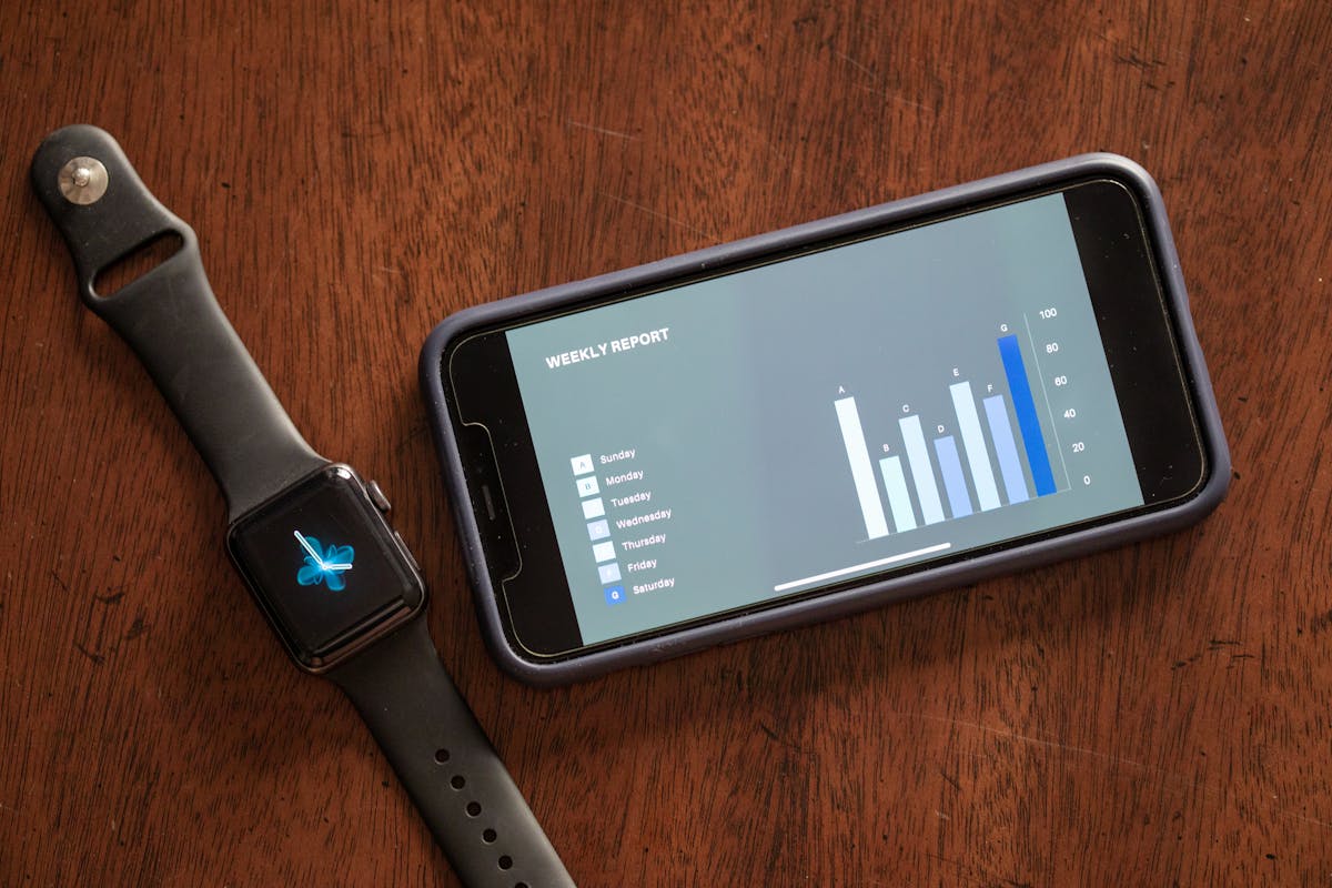 Smartphone e smartwatch affiancati su tavolo di legno inquadrati dall’alto
