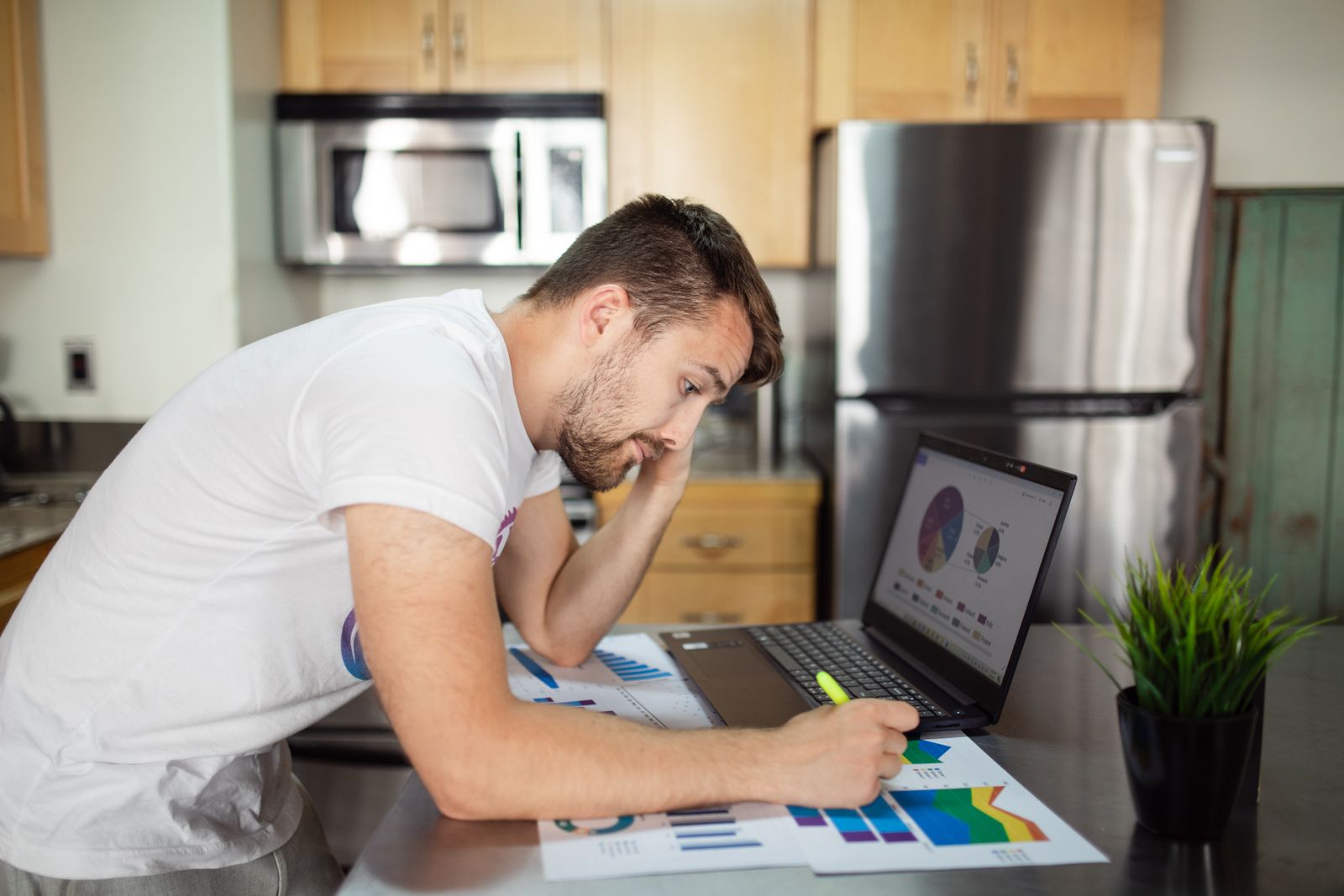 A man reviewing financial charts on a laptop at home