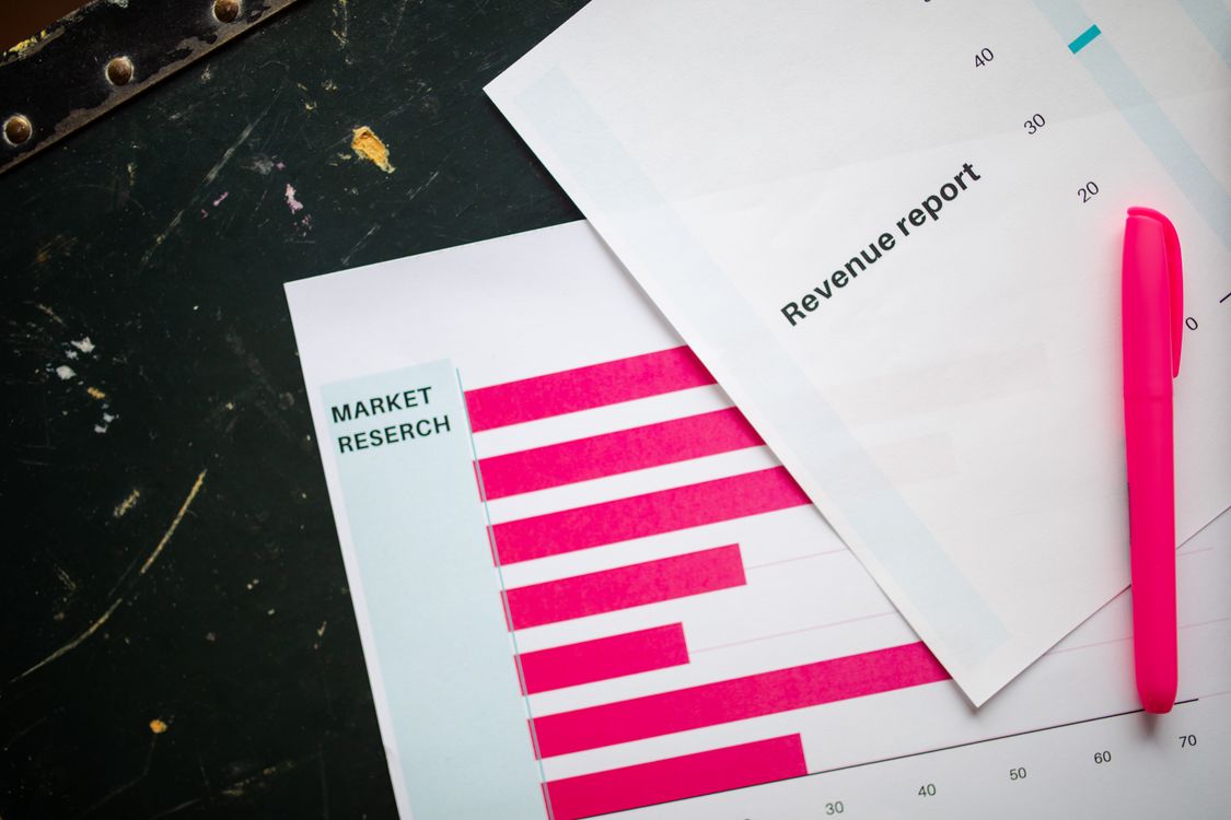 Free Close-up of market research charts and a revenue report with a pink pen on a desk. Stock Photo