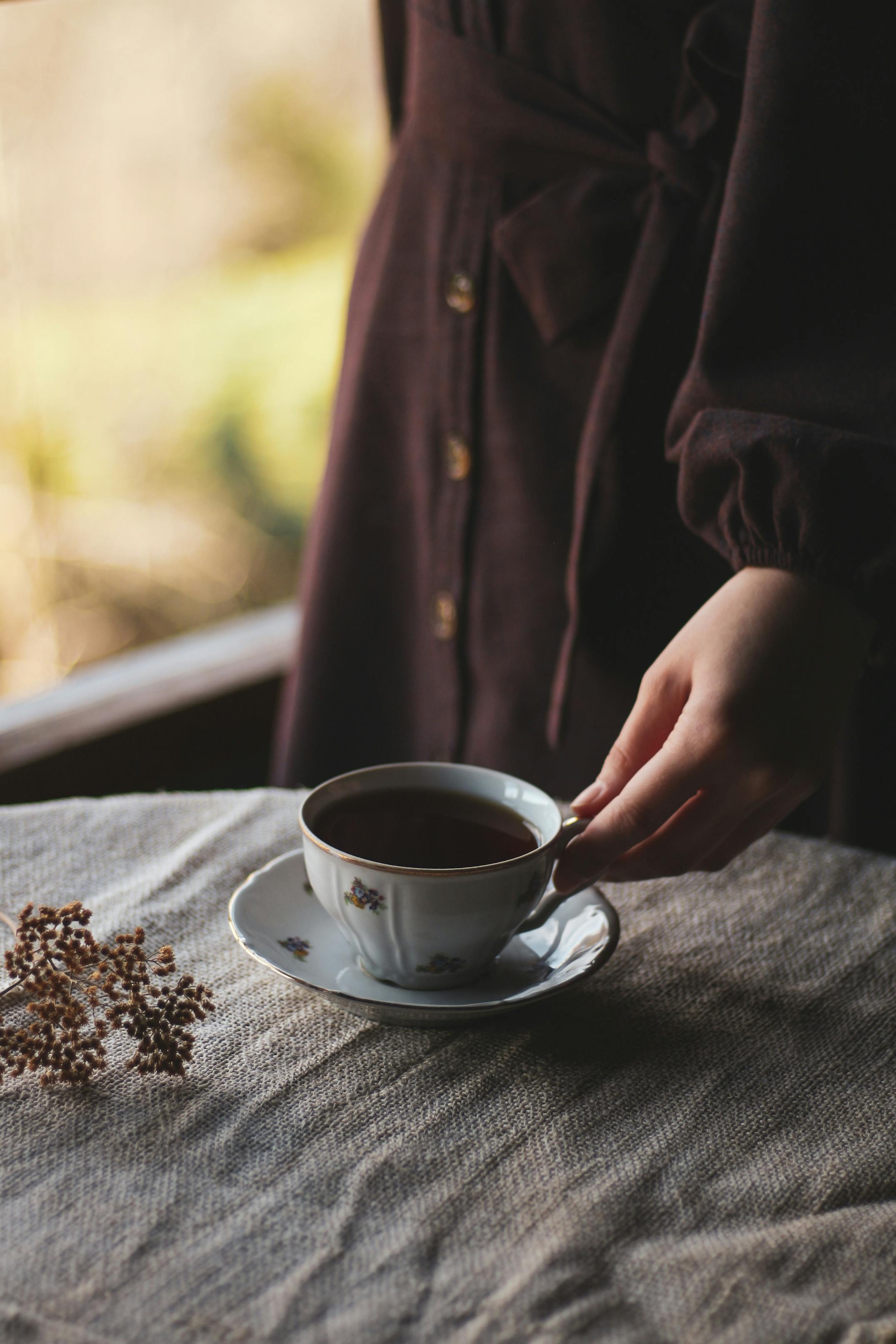 female standing at table and taking cup of coffee