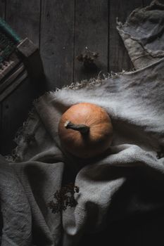 From above of ripe orange pumpkin placed on fabric on wooden floor in dark room