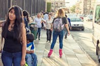 在充满活力的城市街景中，白天一名女子在行人和车流中滑冰