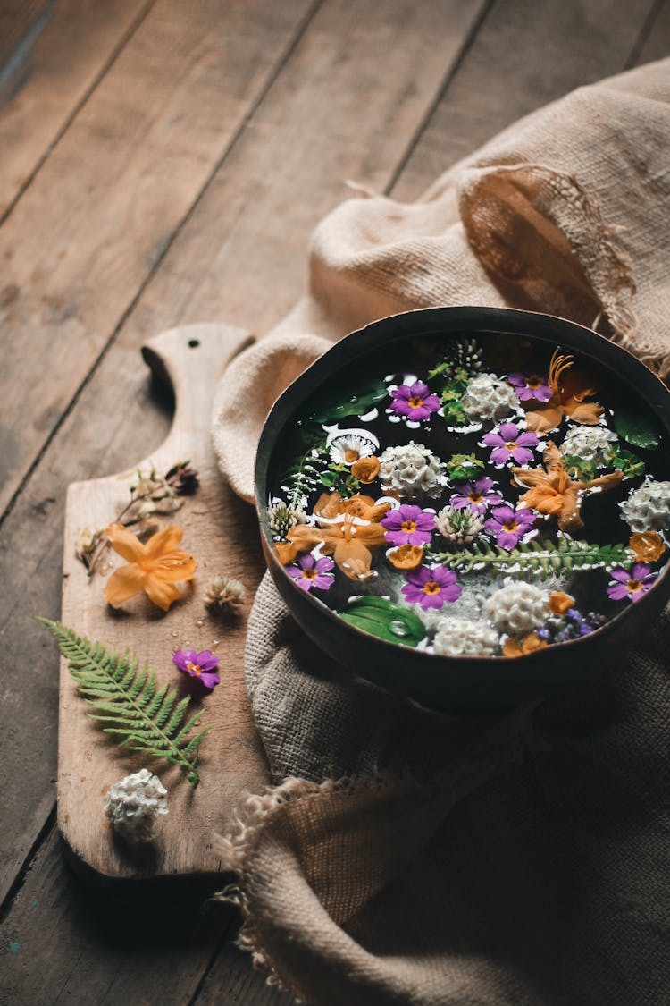 Bowl With Flowers In Water On Fabric Near Cutting Board