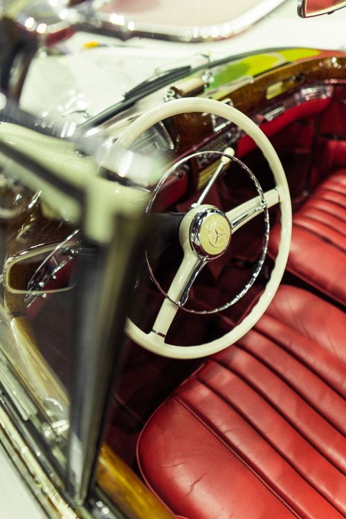 Free High-angle view of a vintage car interior featuring red leather seats and a Mercedes steering wheel. Stock Photo