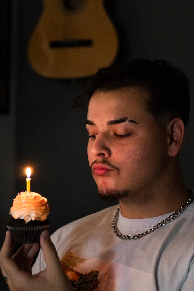 A Man Holding A Cupcake With A Lit Candle